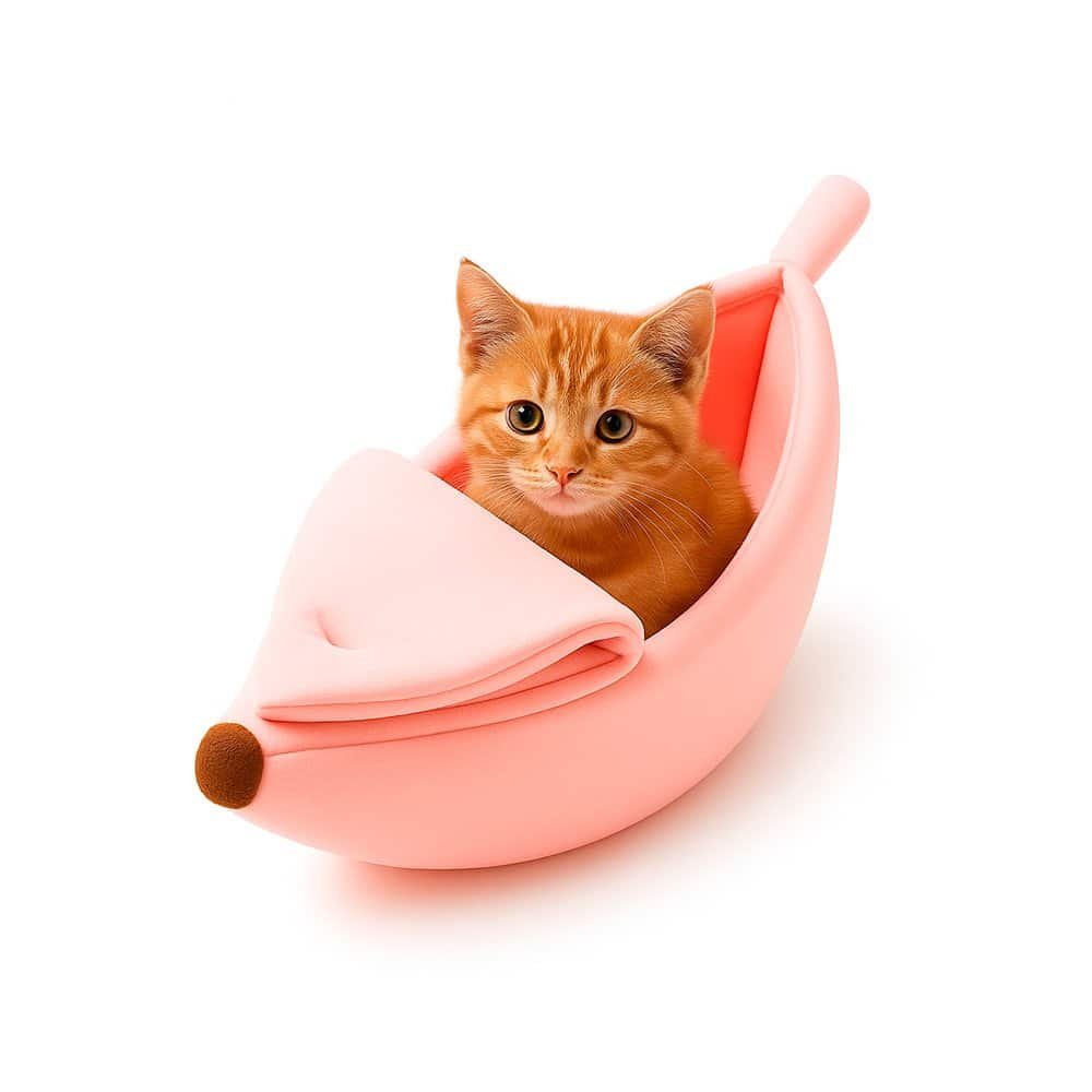 Small kitten comfortably lying inside a banana-shaped plush cat bed